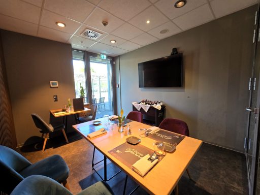 Moderne Besprechungsräume mit Tisch, Stühlen und Fernseher, große Fenster zur natürlichen Beleuchtung.