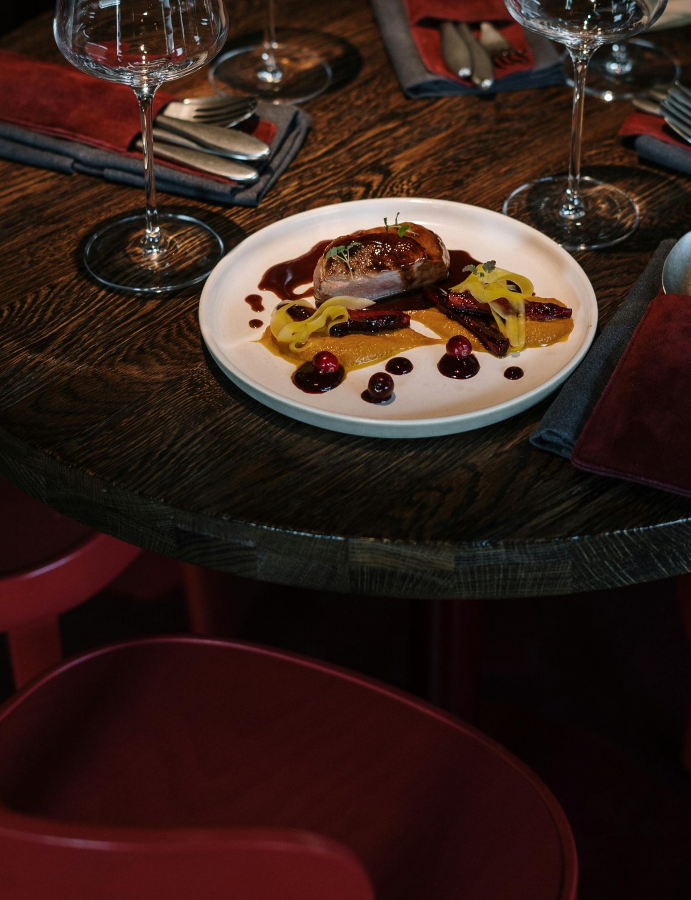 Festlich gedeckter Tisch mit einem Teller einer Fleischspeise und Beeren.