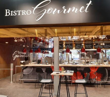 Modernes Bistro mit Theke, roten Pendelleuchten und eleganter Inneneinrichtung.
