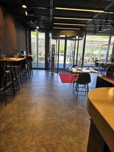 Moderne Café-Umgebung mit Barhockern, Tischen und einer roten Matte am Eingang.