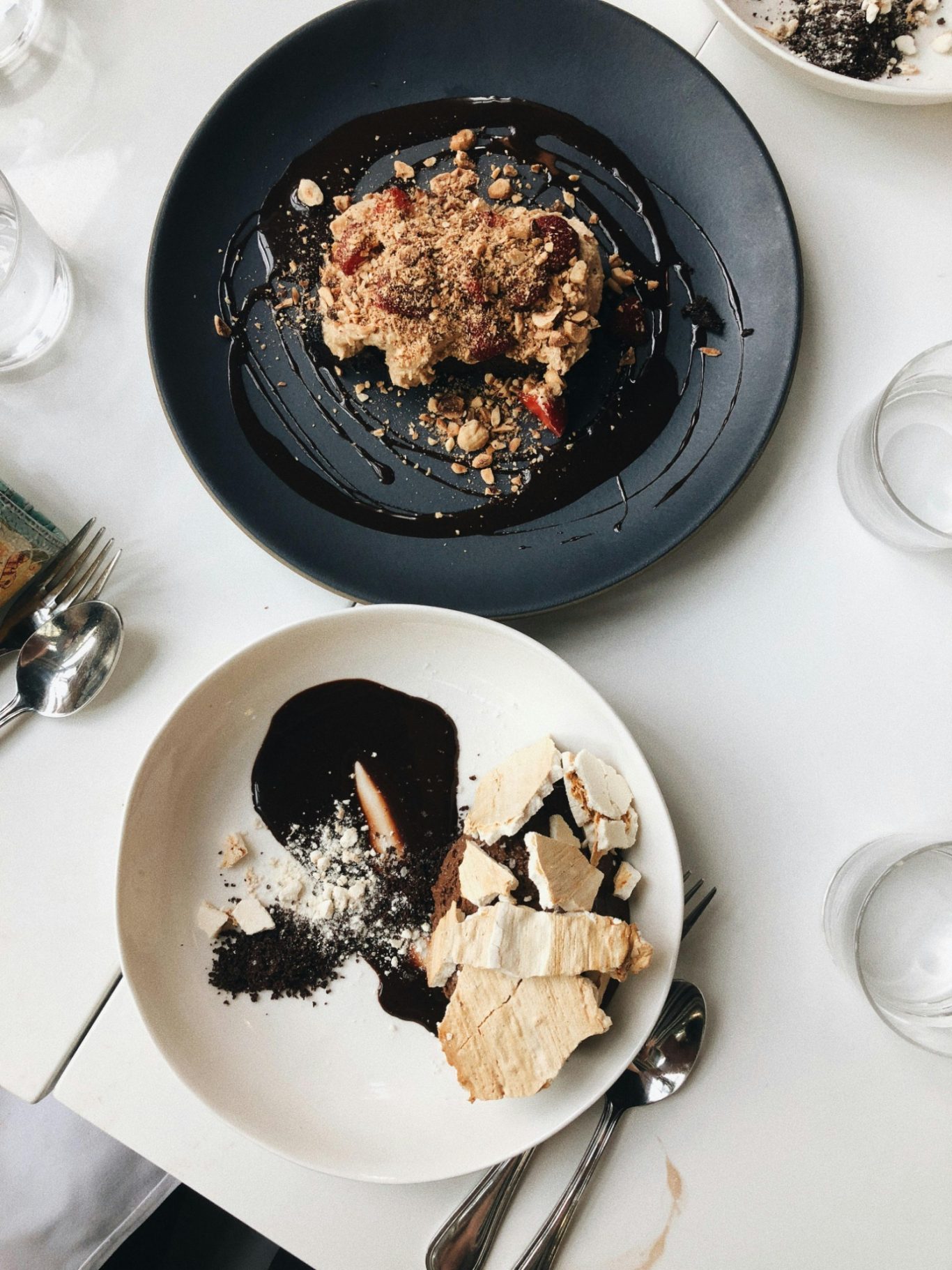 Ein Teller mit Schokoladendessert und ein zweiter mit Obstauflauf und Sahne.