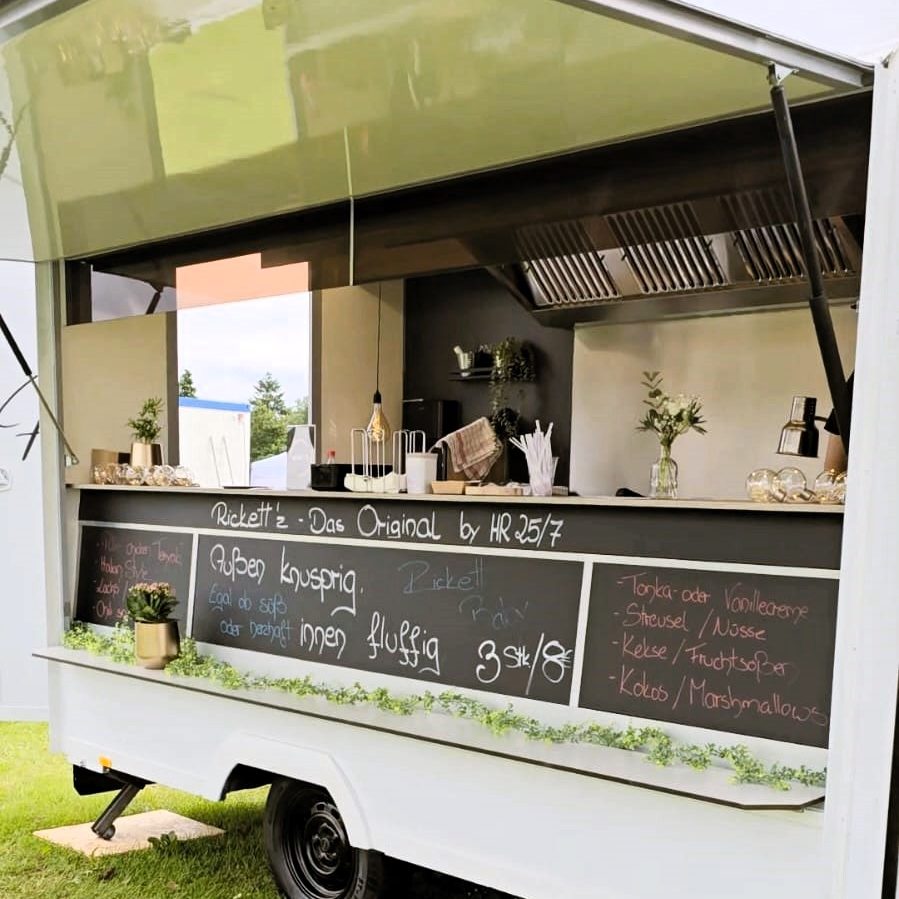 Ein Foodtruck mit schwarzer Tafel, der Speisen und Getränke anbietet.
