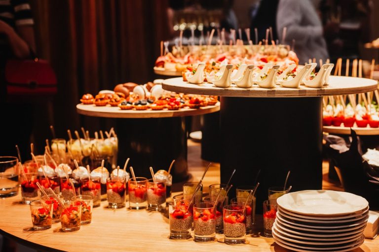 Ein Buffet mit verschiedenen Fingerfood in Gläsern und auf Tellern, kreativ dekoriert.